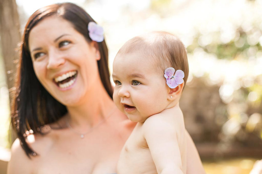 Outdoor Fotografie, Mutter und Baby, die mit Blumen auf ihrem Kopf lachen