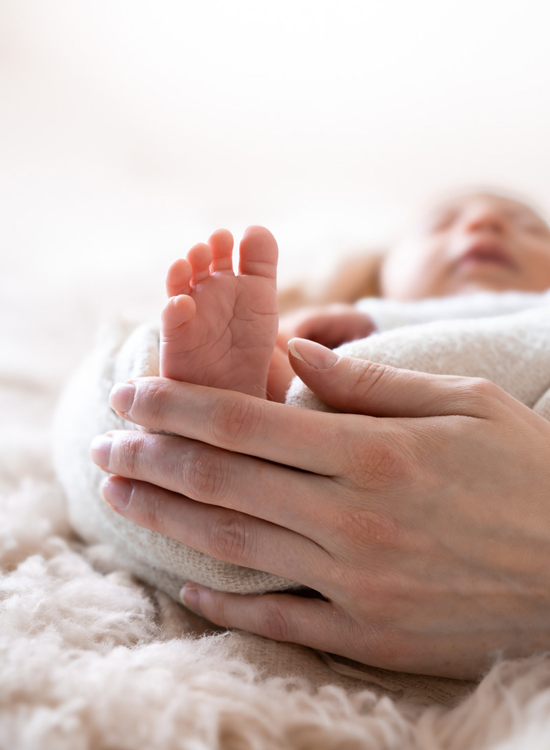 DSC06603-neugeborenen-fotografie Hand einer Mutter hält den kleinen Fuß ihres Neugeborenen beim Fotoshooting in Berlin